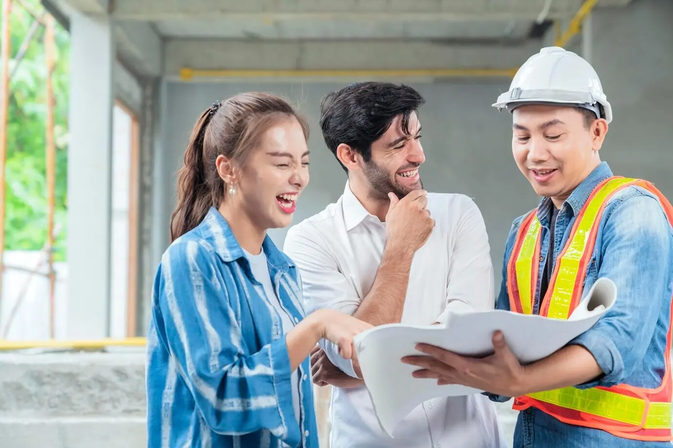 A happy site inspection engineer and an Asian female client casually meet together at a home renovation site, with the structure in the background.